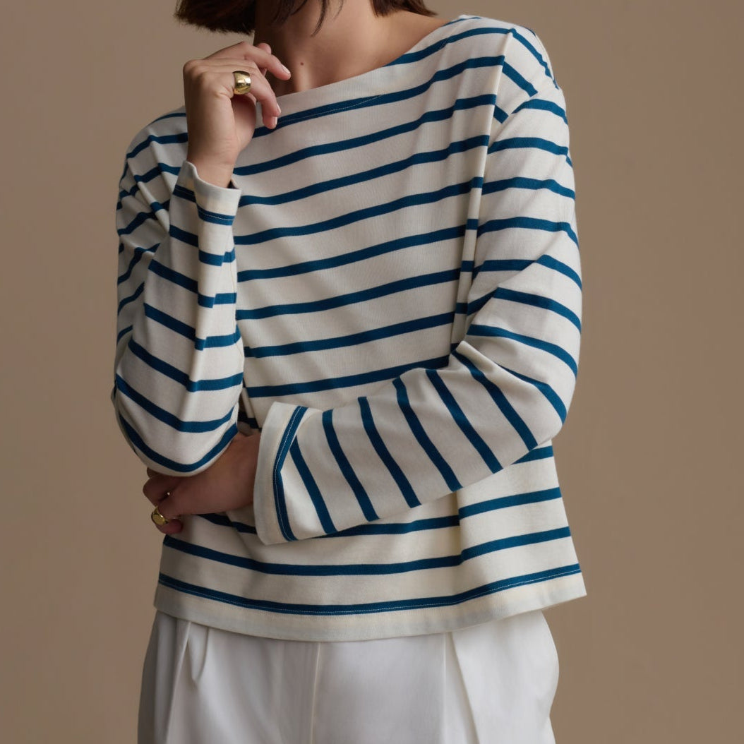 Woman wearing a blue and white striped sweater against a beige background