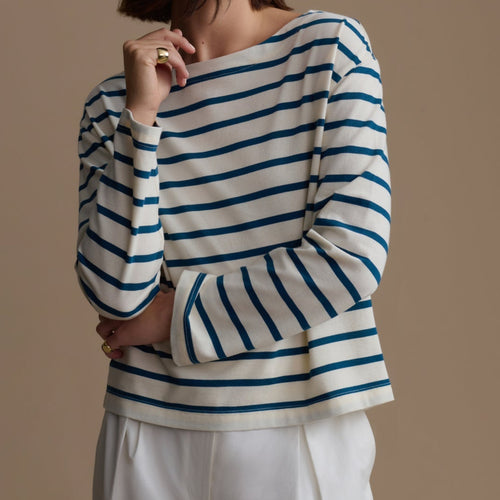 Woman wearing a blue and white striped sweater against a beige background