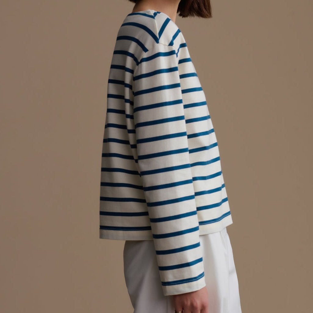 Woman wearing a blue and white striped sweater against a beige background