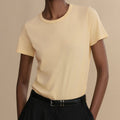 Woman wearing a light yellow t-shirt against a beige background