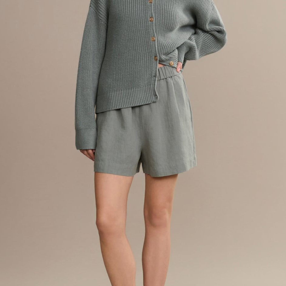 Woman wearing a gray knit outfit on a beige background