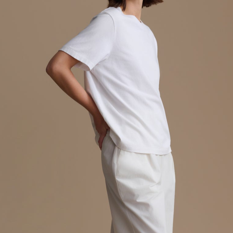 Woman wearing a white outfit standing against a beige background