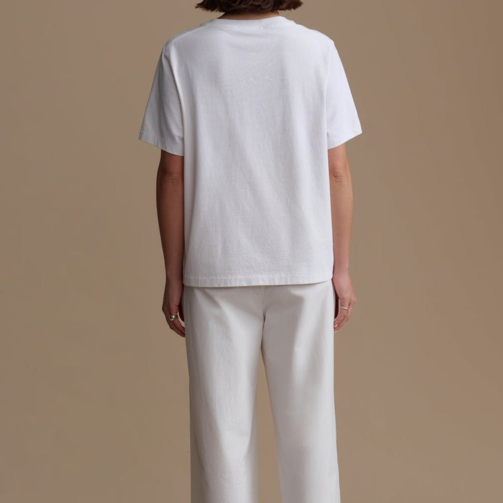 Person wearing a white t-shirt and pants on a beige background