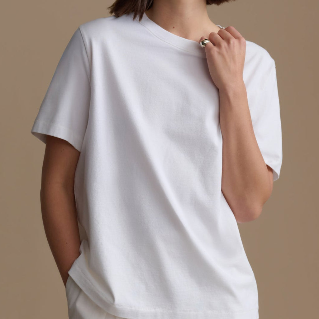 Woman wearing a white t-shirt against a beige background