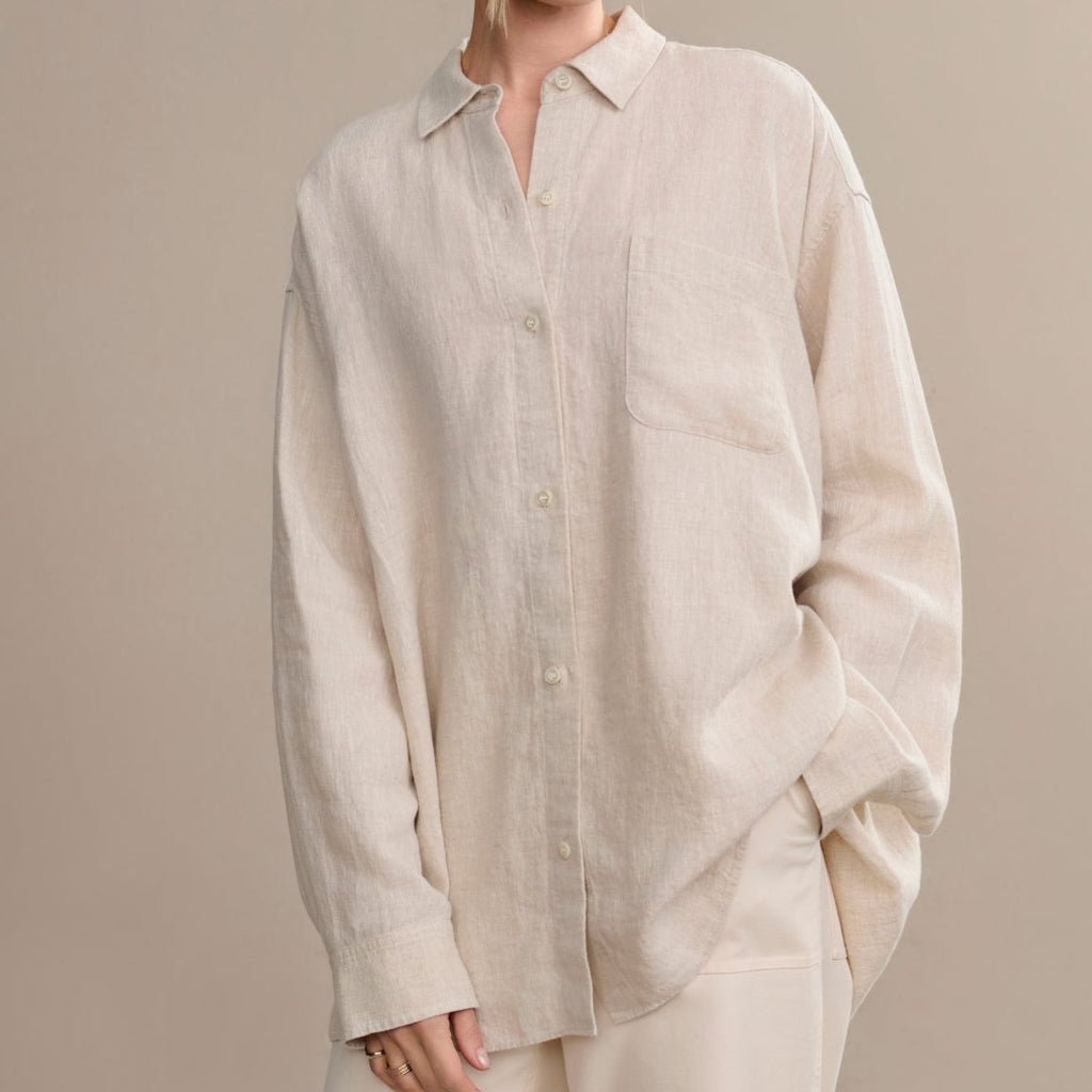 Woman wearing a beige linen shirt against a plain background