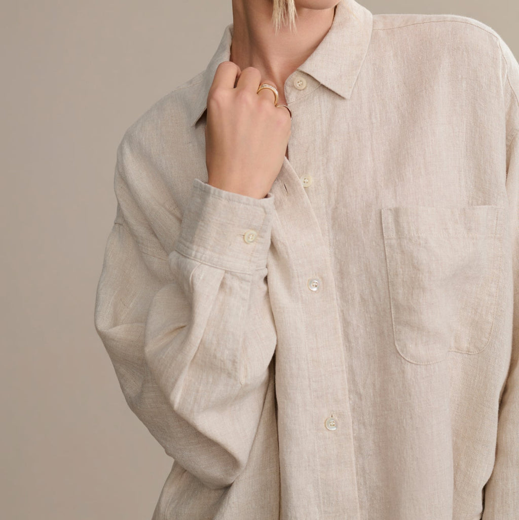 Beige linen shirt worn by a person on a neutral background