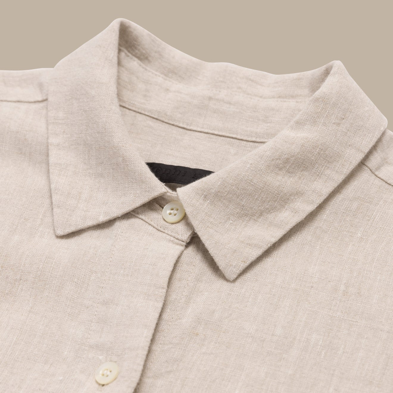 Close-up of a beige shirt collar with buttons on a neutral background