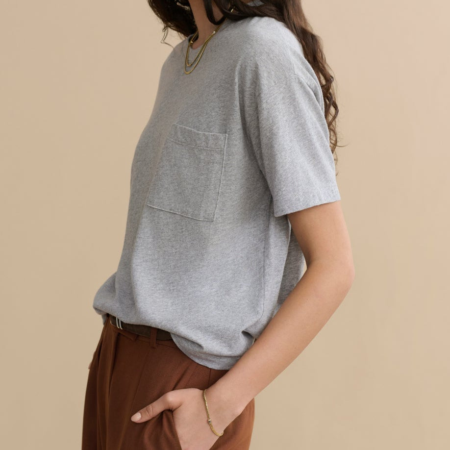 Woman wearing a gray top and brown pants on a beige background