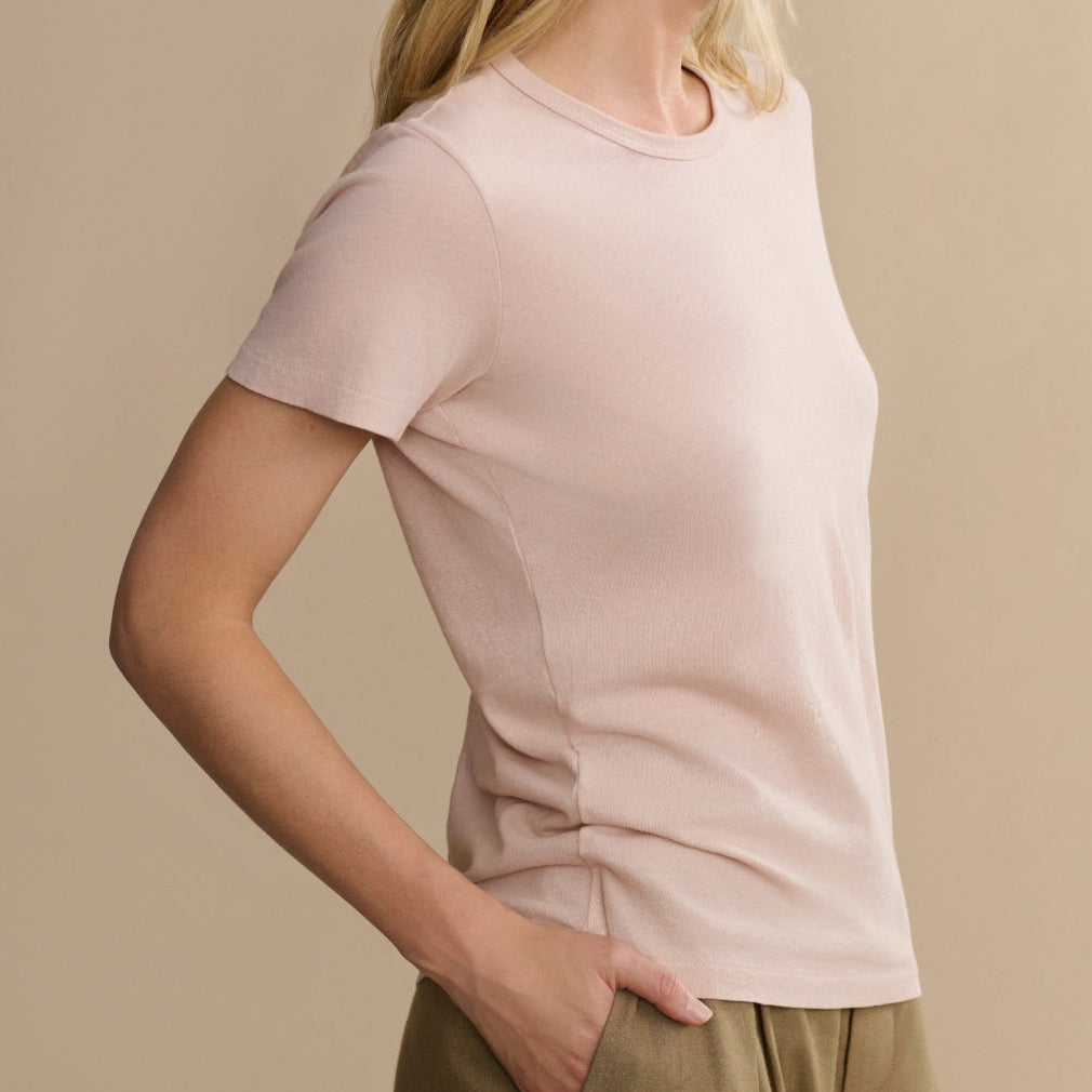 Woman wearing a light pink t-shirt against a beige background