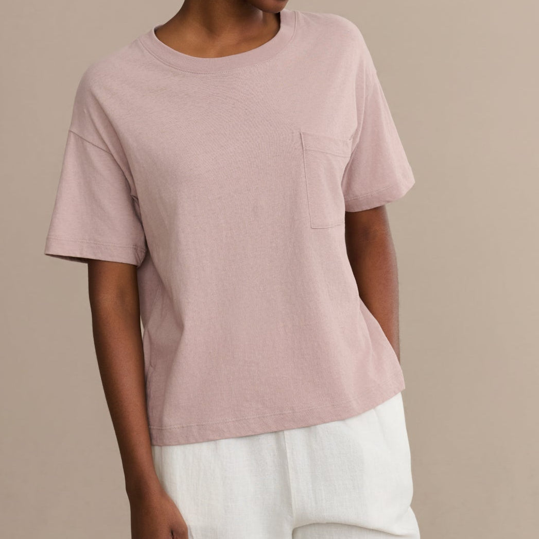 Woman wearing a light pink t-shirt with a pocket on a beige background