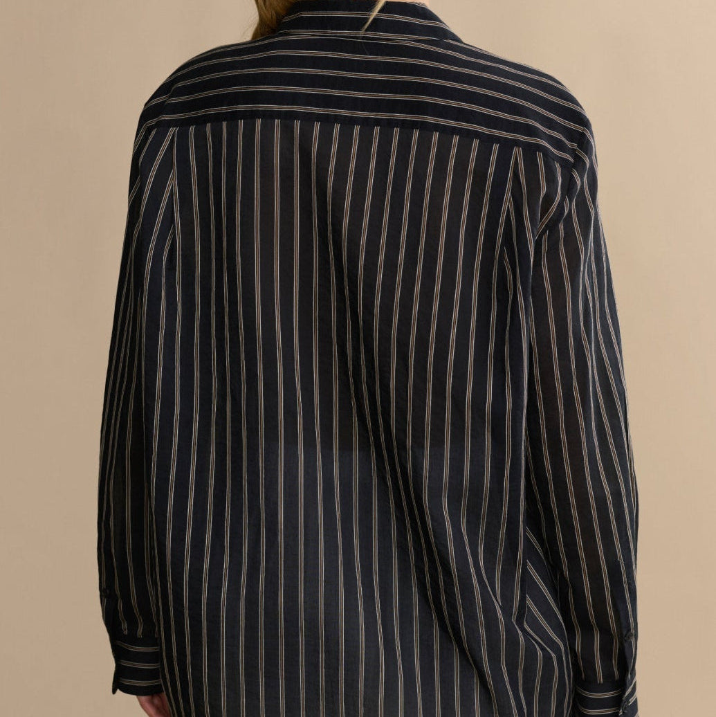 Woman wearing a black and white striped shirt against a beige background