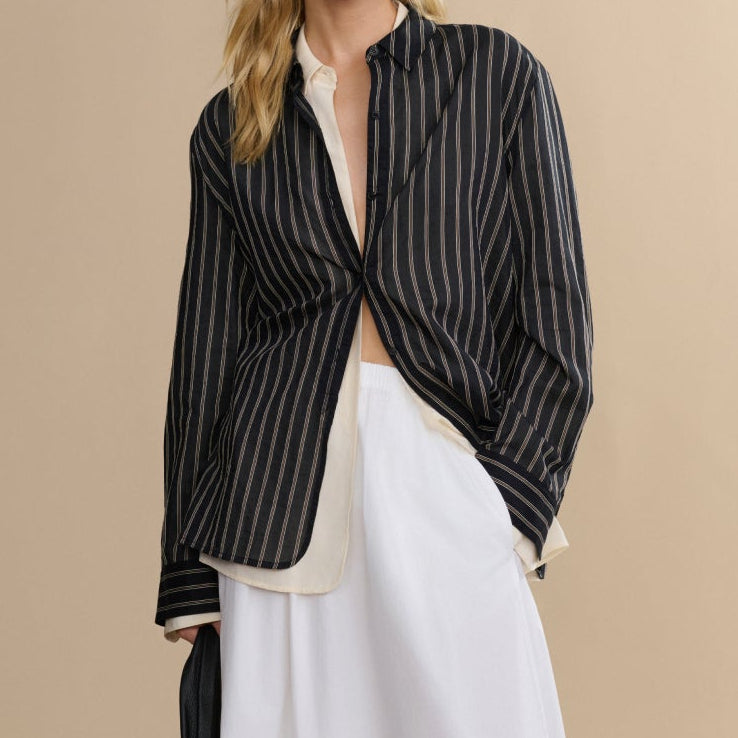 Woman wearing a black and white striped shirt with a white skirt on a beige background