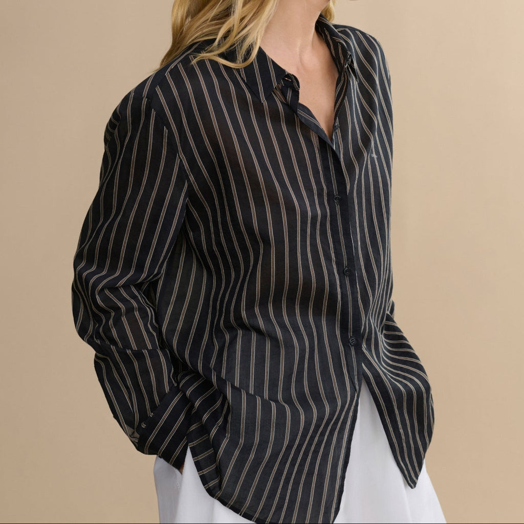 Woman wearing a black and white striped shirt against a beige background