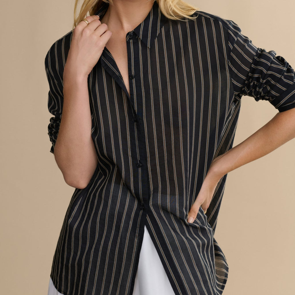 Woman wearing a black and white striped shirt against a beige background
