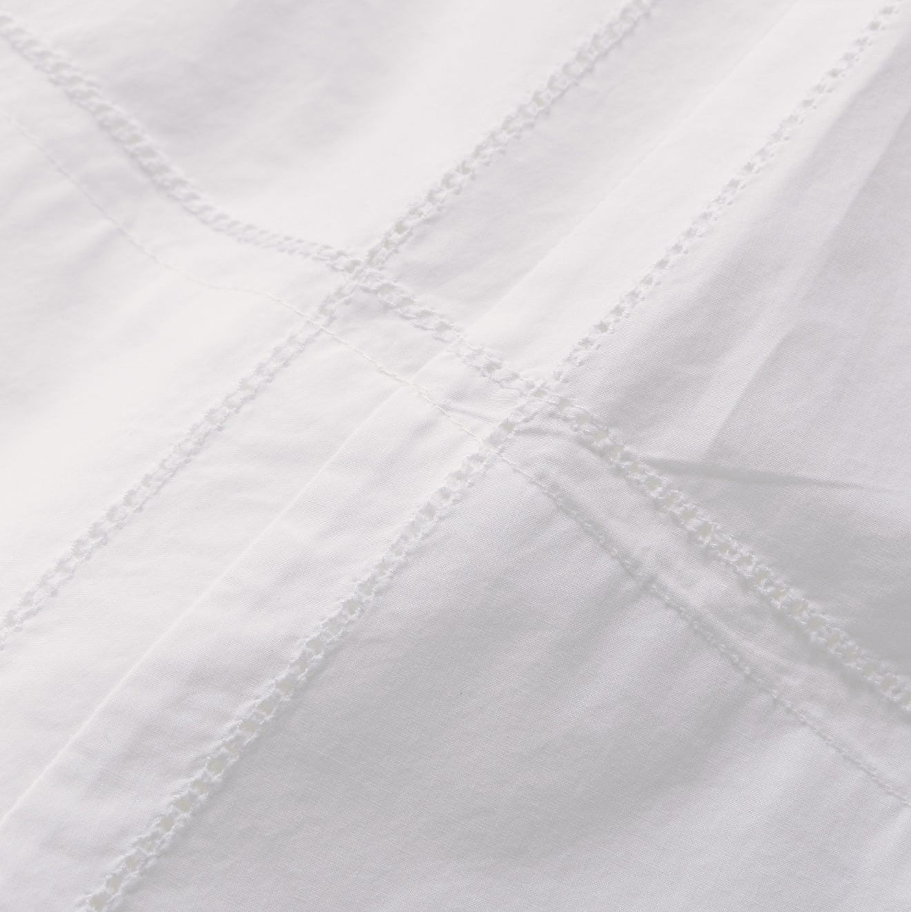 Close-up of a white quilted fabric with diagonal stitching pattern