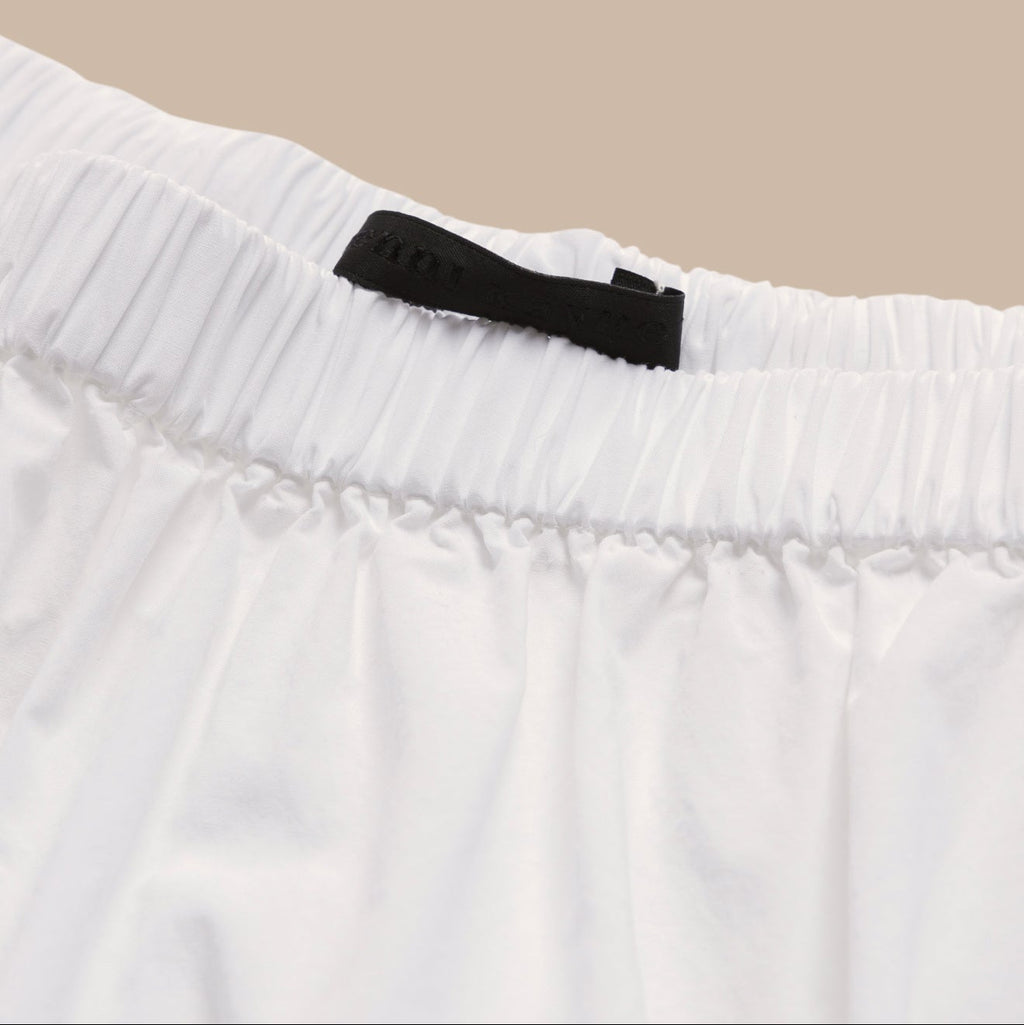 Close-up of a white garment with a black label on a beige background