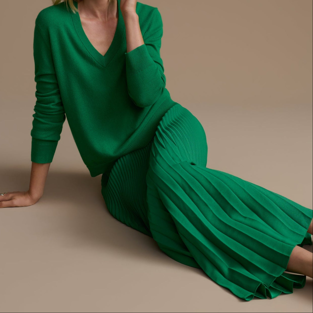 Woman wearing a green dress sitting on a beige background