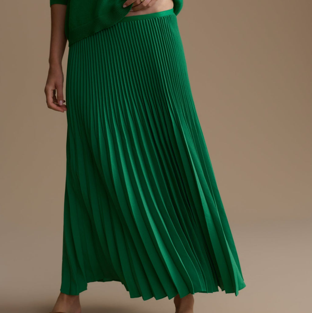 Green pleated skirt worn by a person on a beige background