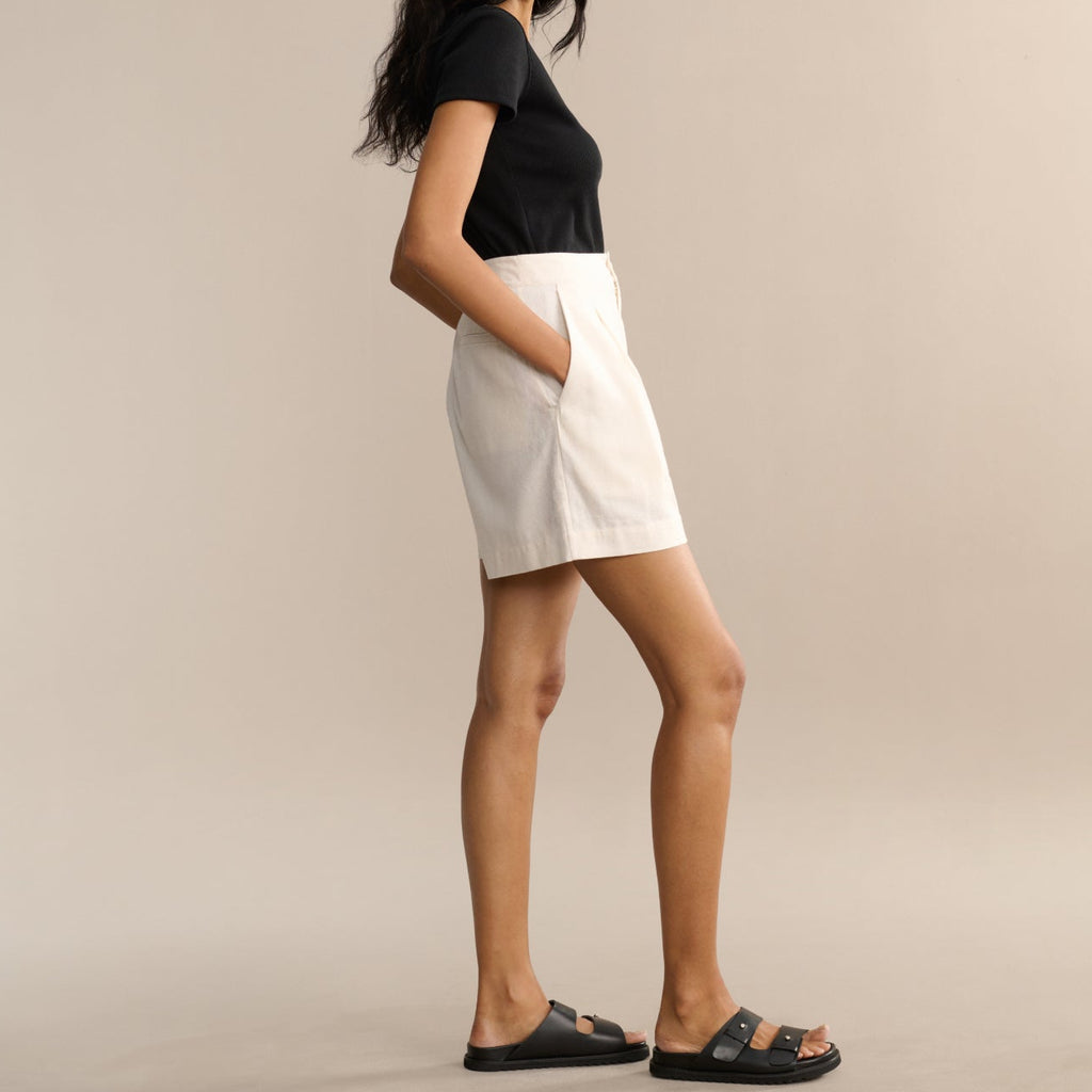 Woman wearing a black top and white skirt on a beige background