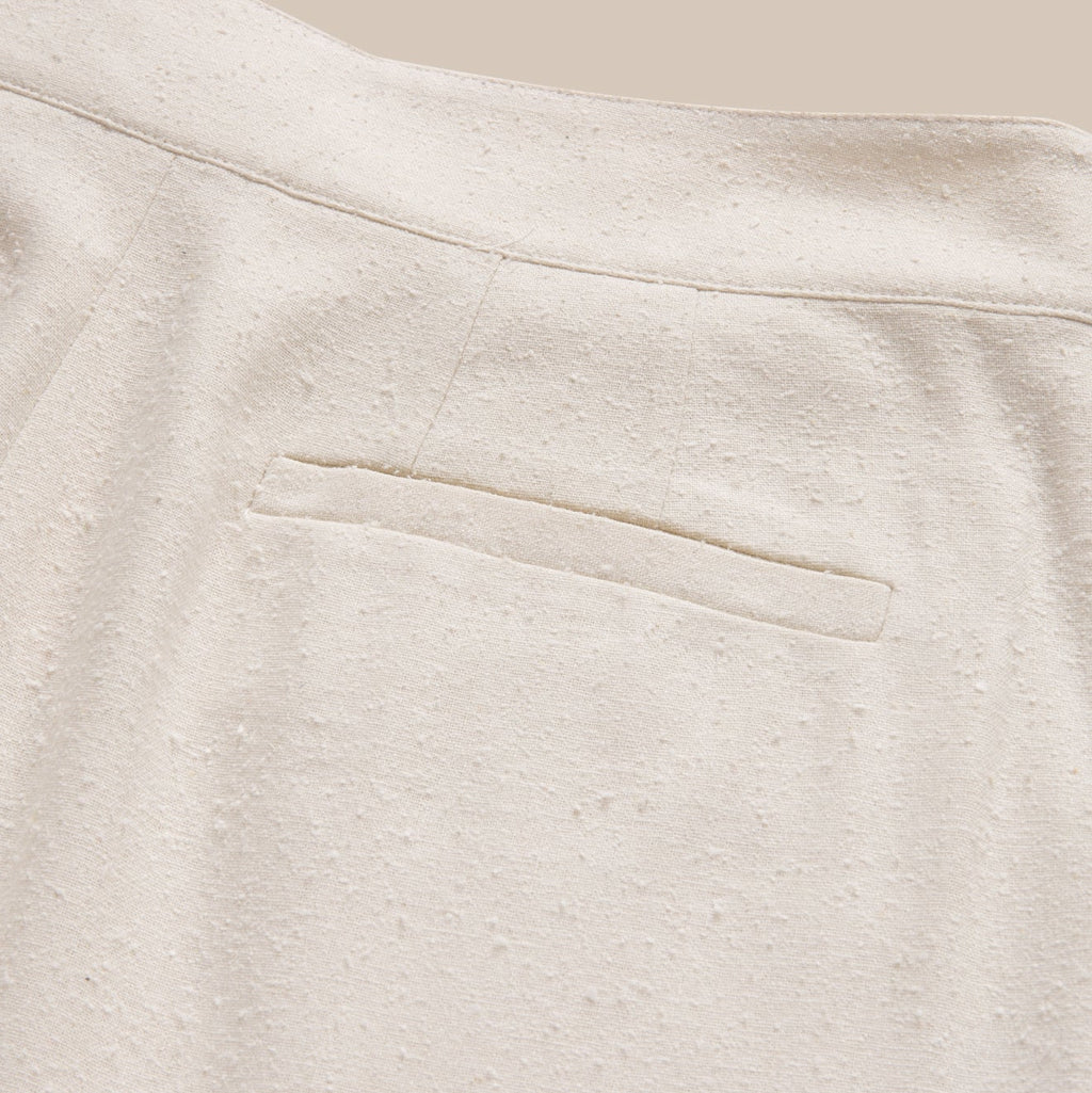 Close-up of a textured beige fabric with a pocket detail.