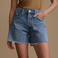 Person wearing blue denim shorts on a beige background