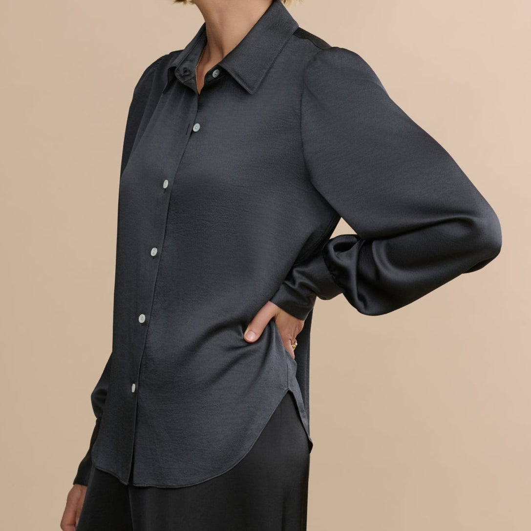 Woman wearing a dark gray blouse against a beige background